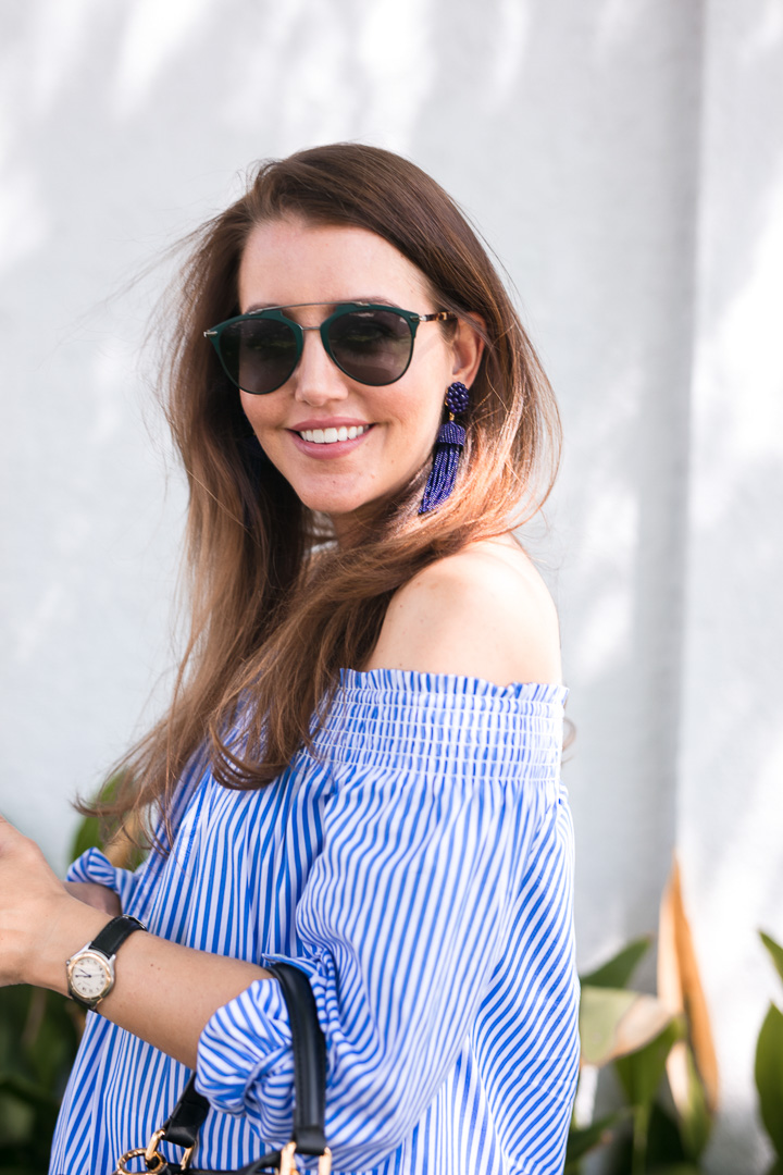 Amy Havins wears a blue and white off the shoulder blouse and white shorts.